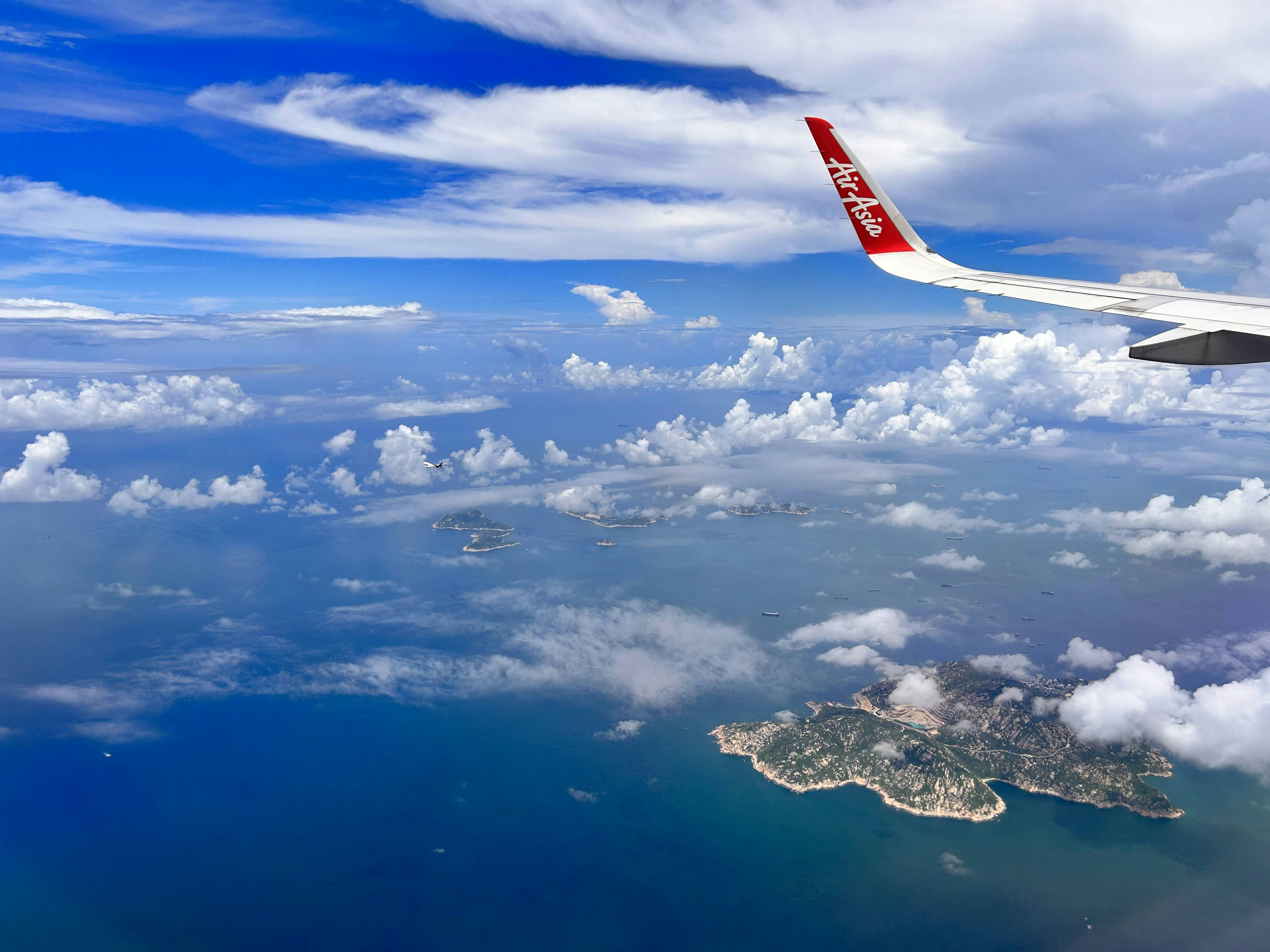 a view of the wing of an airplane flying over a body of water