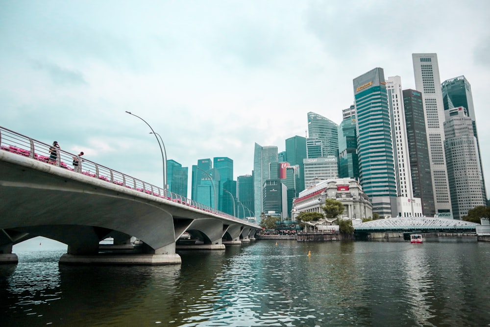 a bridge over a body of water with tall buildings in the background