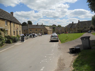 A cozy village street in Niolu with locals chatting and a bus stop sign.
