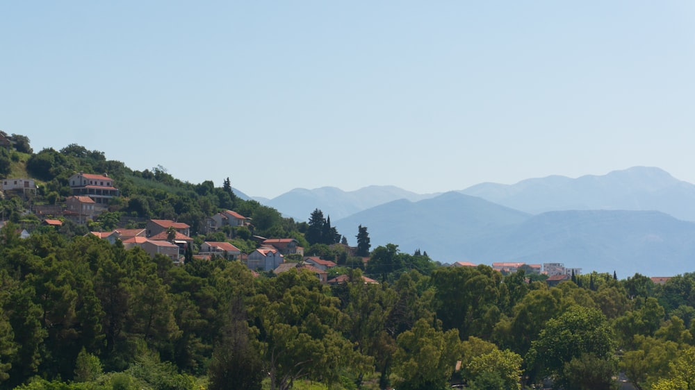 a small village nestled on a hillside with mountains in the background