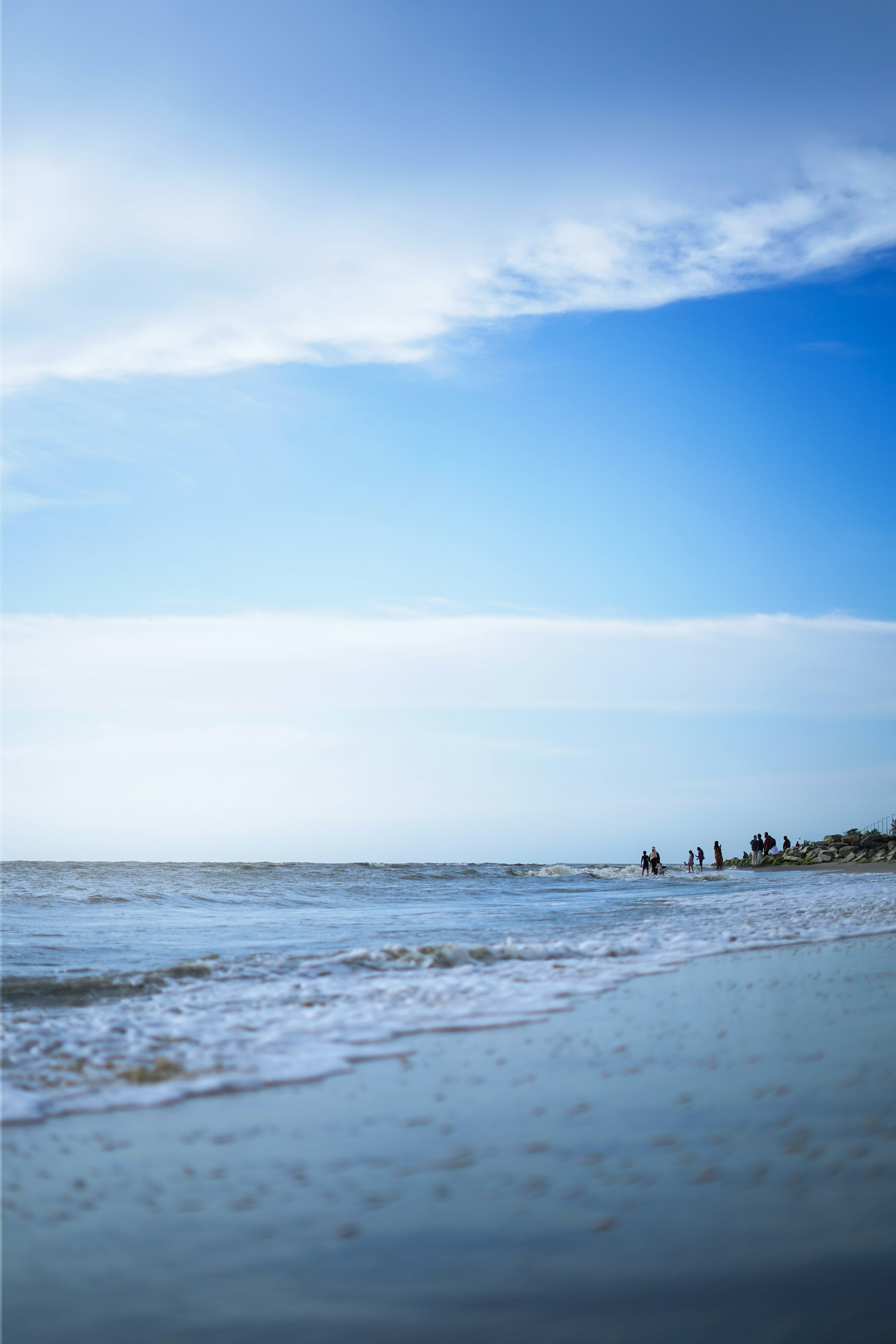 a group of people standing on top of a beach next to the ocean