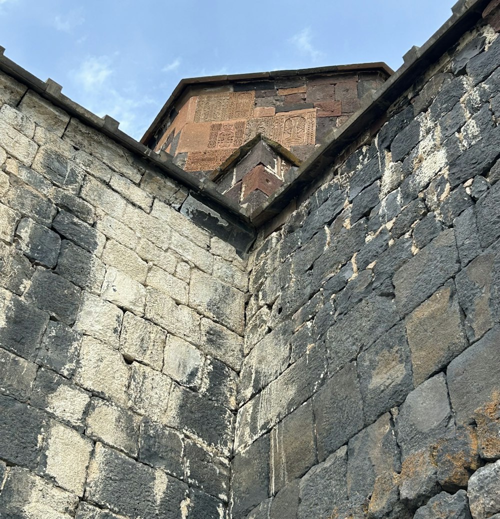 Un muro de piedra con una torre del reloj al fondo