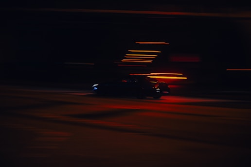 Abstract silhouette of two cars converging with dynamic motion blur in red and carbon black tones.
