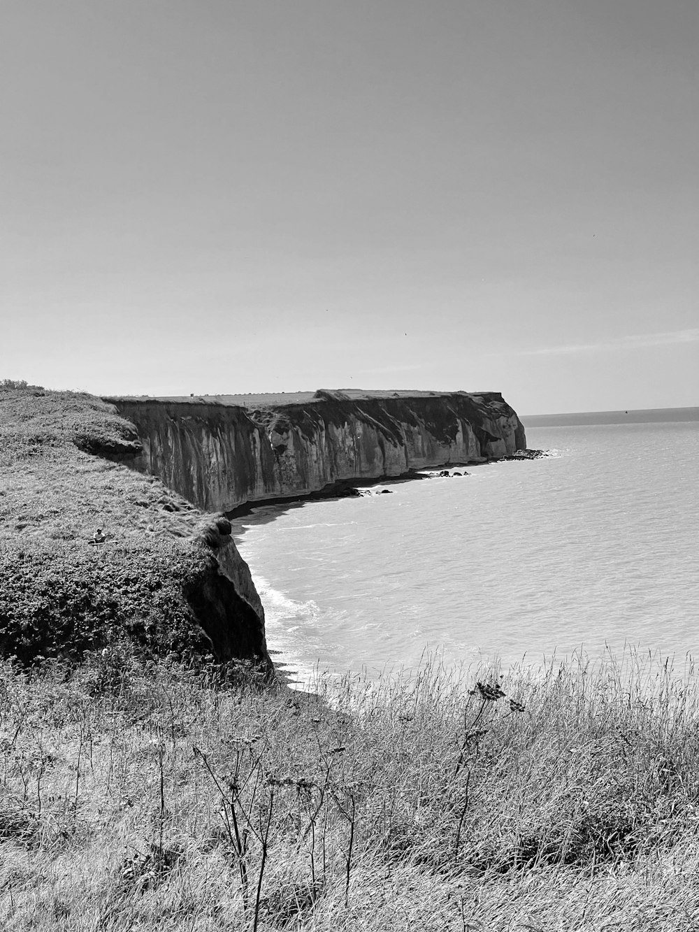 uma foto em preto e branco de um penhasco à beira-mar