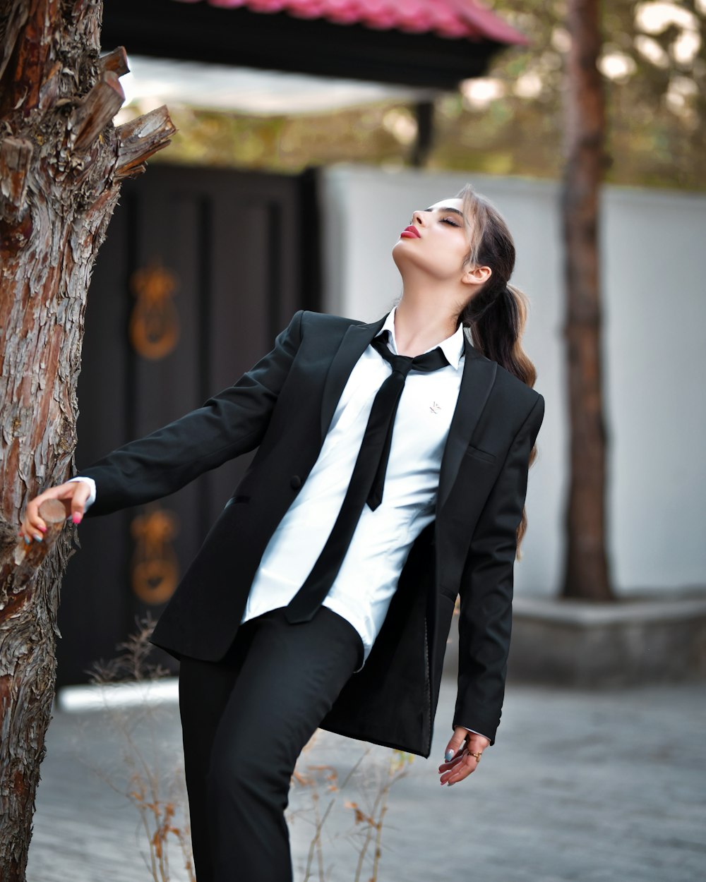 Une femme en costume appuyée contre un arbre