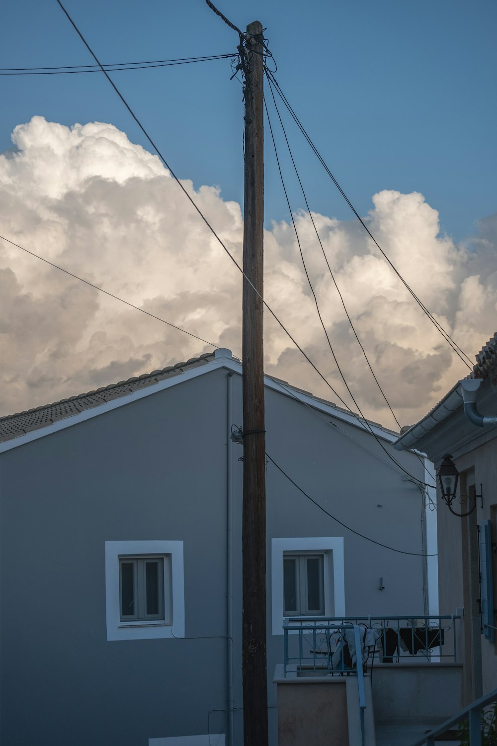 a telephone pole in front of a house with a cloudy sky in the background
