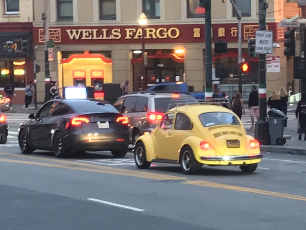 a group of cars driving down a street next to a tall building