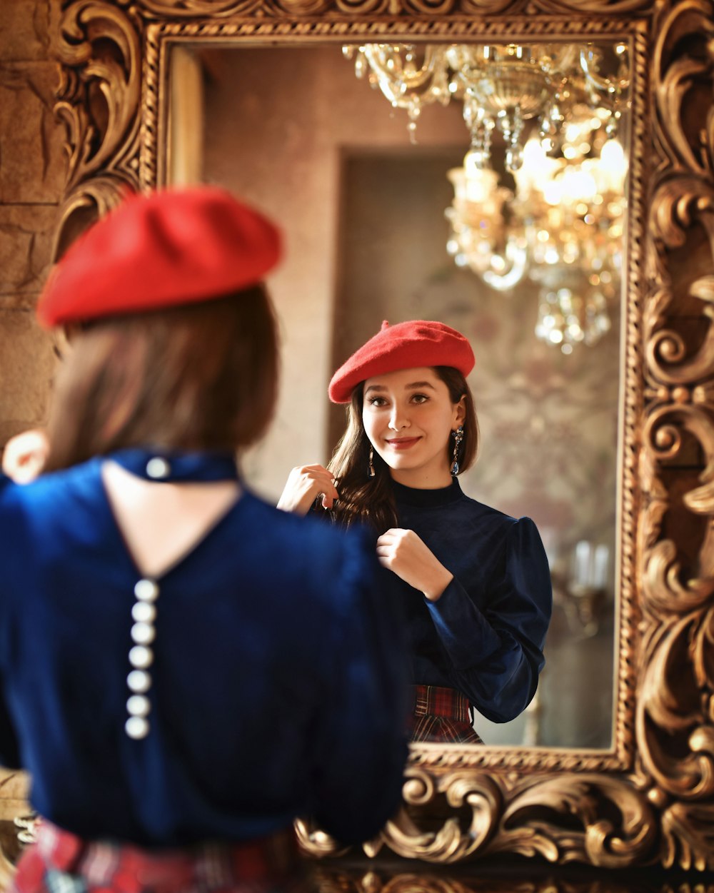 赤い帽子をかぶった女性が鏡で自分を見ている