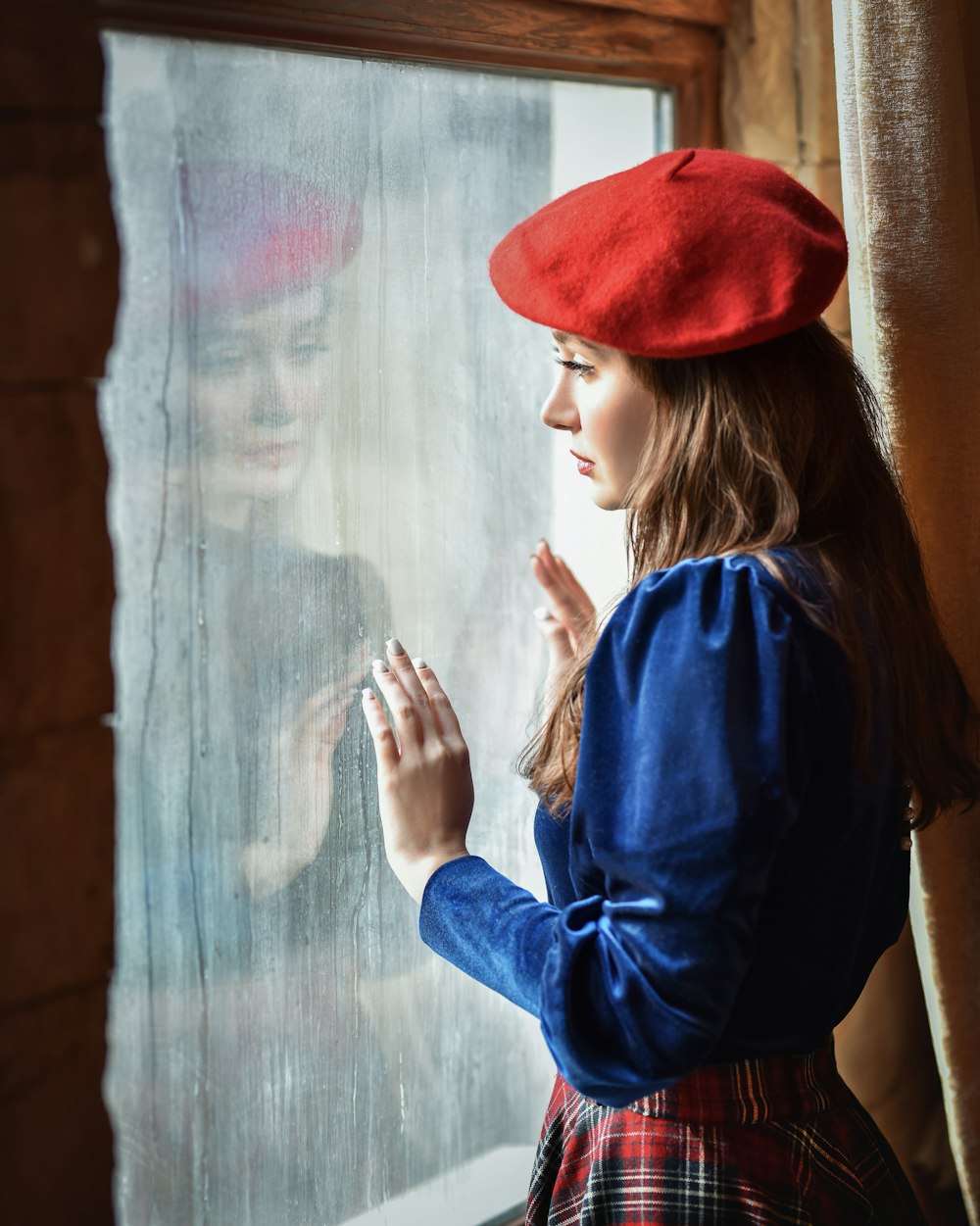 a woman in a red hat looking out a window