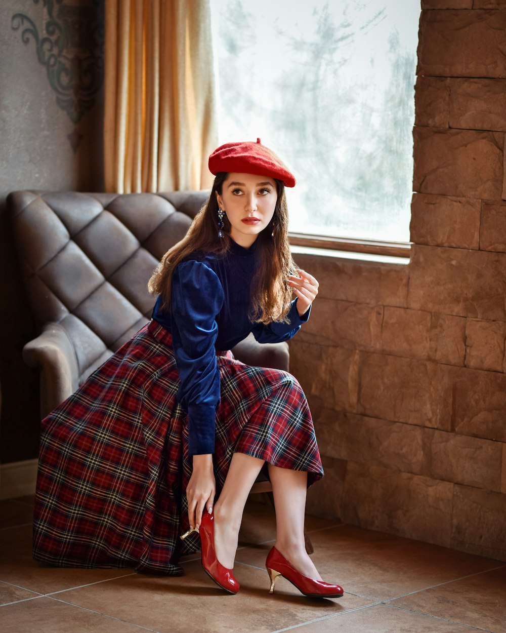 a woman sitting on a couch wearing a red hat