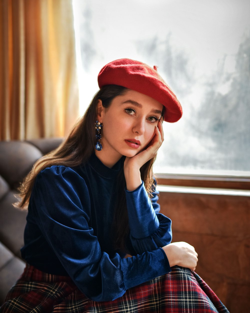 a woman sitting on a couch wearing a red hat