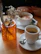 A group of friends laughing around a wooden table with steaming coffee cups.