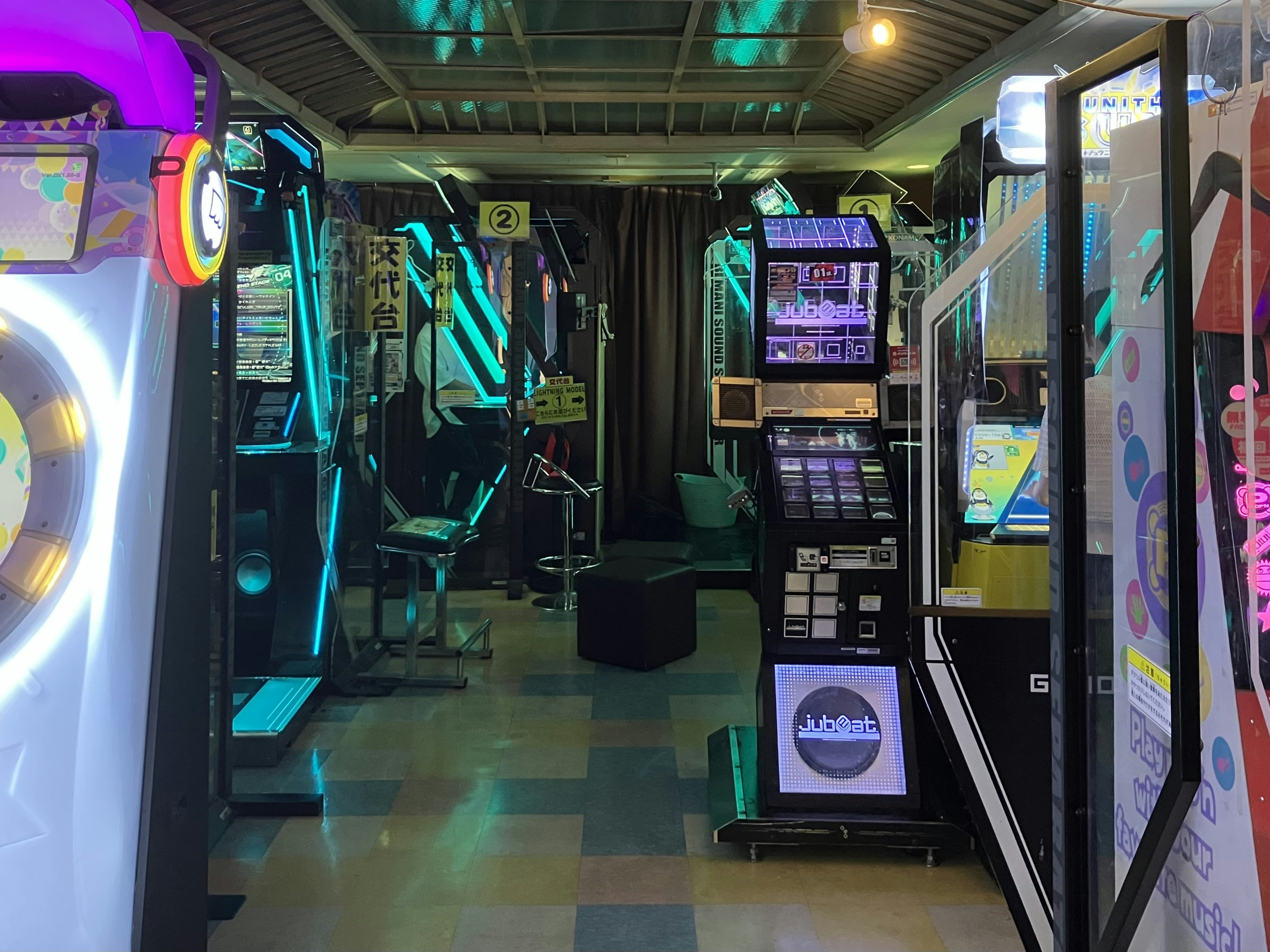 Arcade game machines with colorful screens and flashing lights in a busy arcade hall