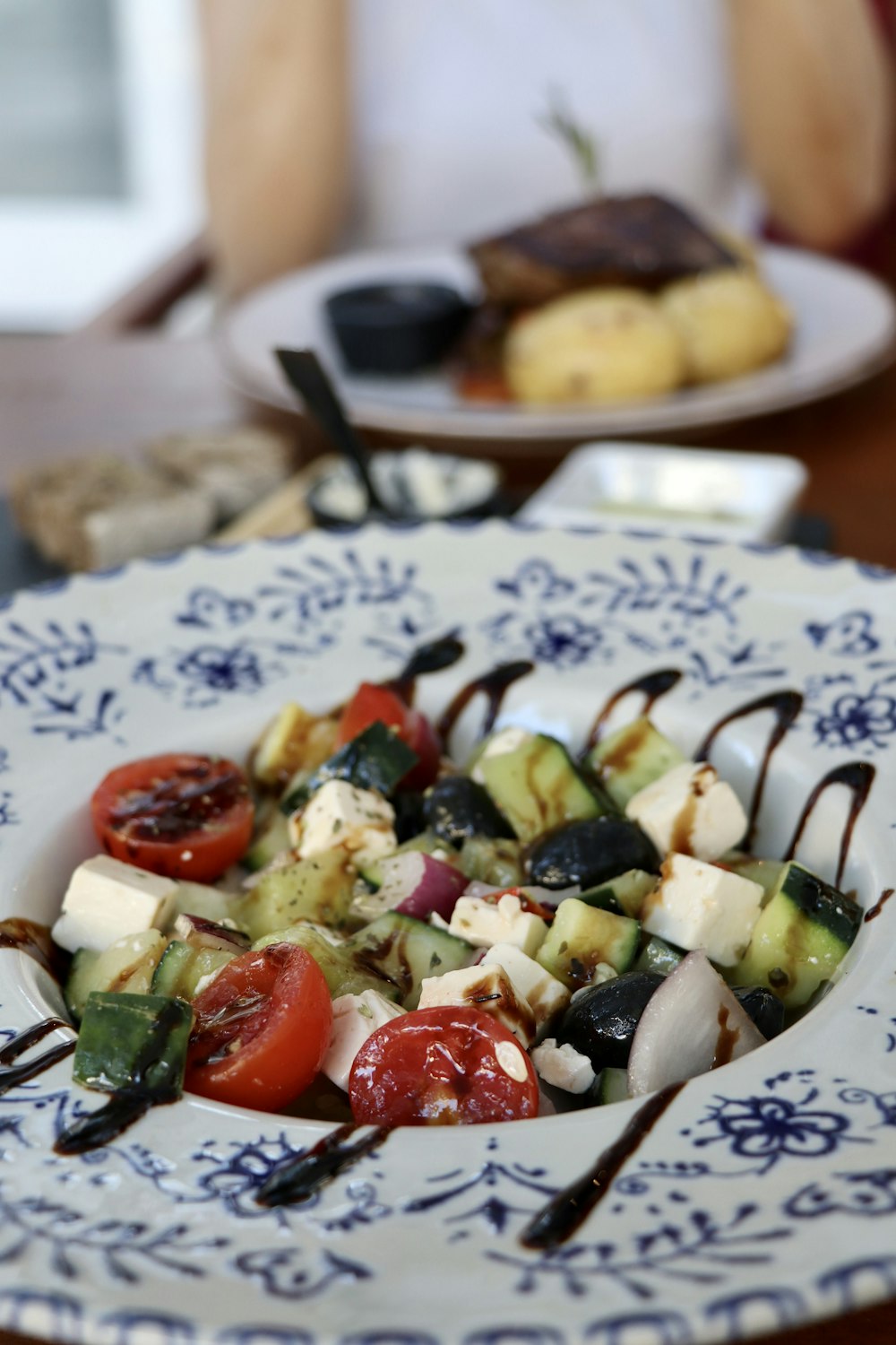 a white and blue plate topped with cucumbers and tomatoes