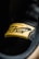 A close-up view of a yellow fabric label with the word 'Nike' and the swoosh logo, stitched onto a black surface. The texture of the fabric and stitching details are clearly visible.
