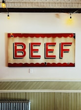 A rustic wooden sign hanging on a barn door with 'Grass-Fed Beef' painted in classic lettering.