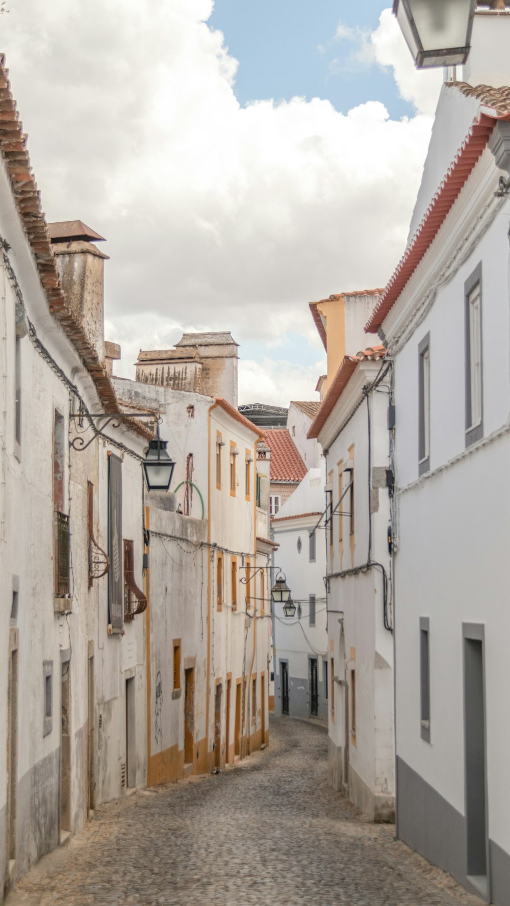 a cobblestone street lined with white buildings