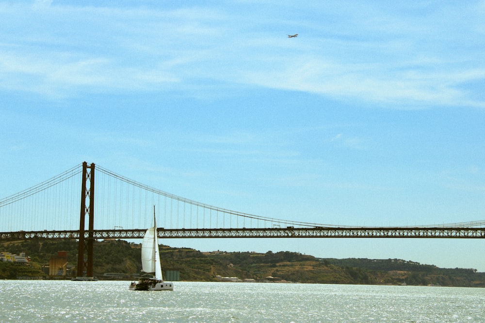 a sailboat in the water near a bridge