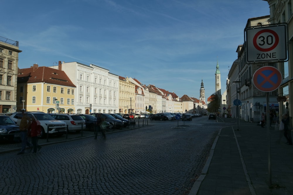 a city street lined with parked cars next to tall buildings