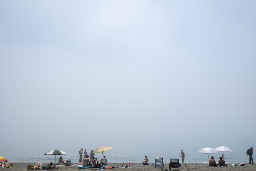 a group of people sitting on top of a sandy beach