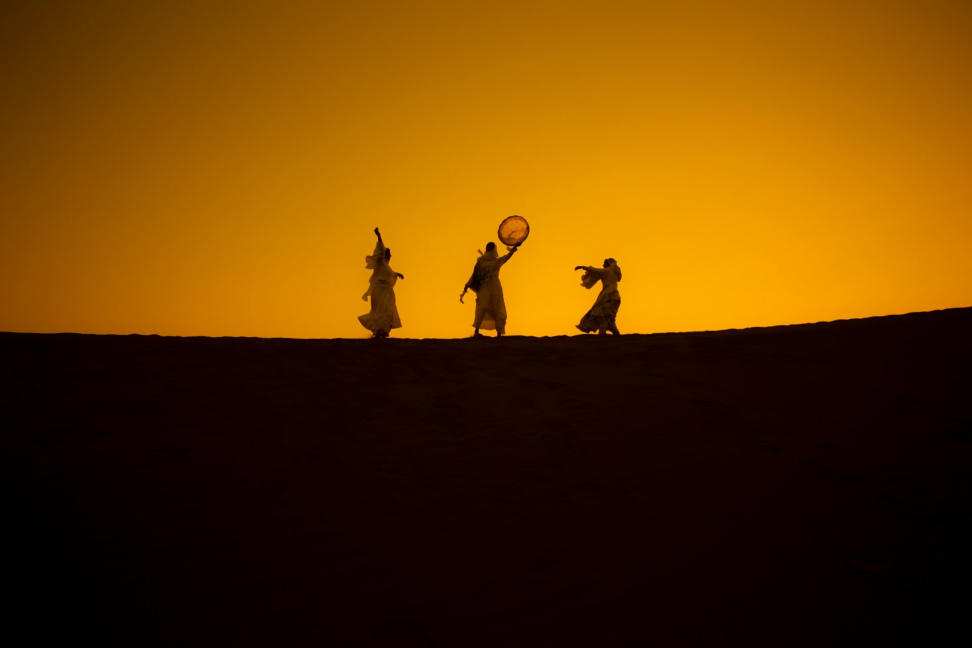 a group of people standing on top of a sandy hill