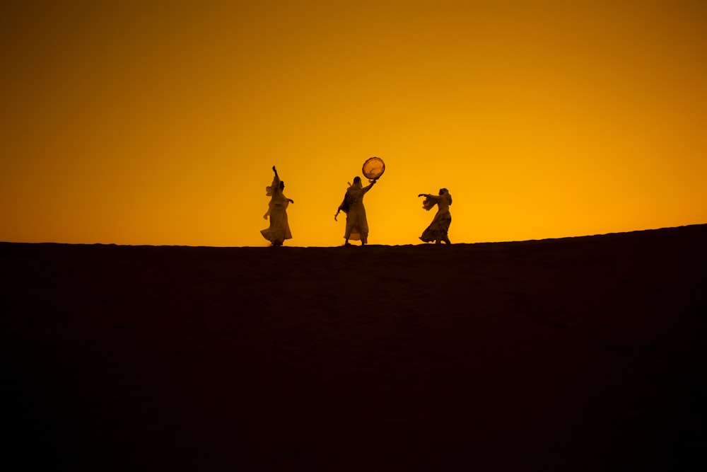 a group of people standing on top of a sandy hill