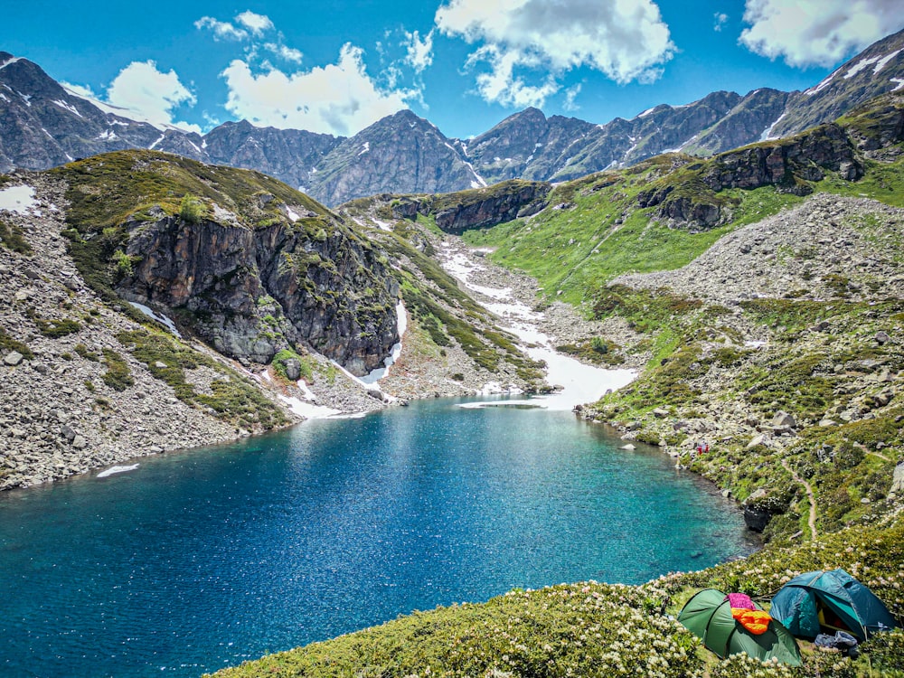 a blue lake surrounded by mountains and grass