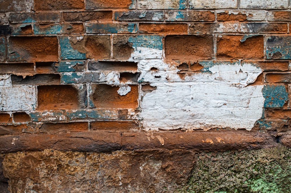 an old brick wall with peeling paint and moss growing on it