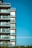 A modern apartment building with multiple floors featuring glass balconies and large windows against a clear blue sky.