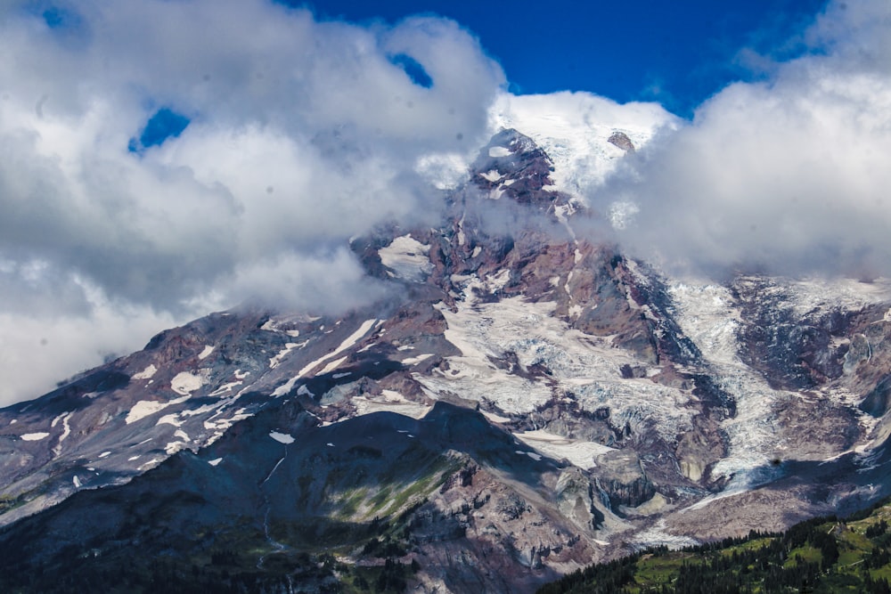 a mountain covered in snow under a cloudy blue sky