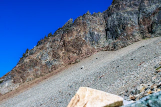 Close-up of rugged mining geology equipment resting on rocky terrain under a clear sky.