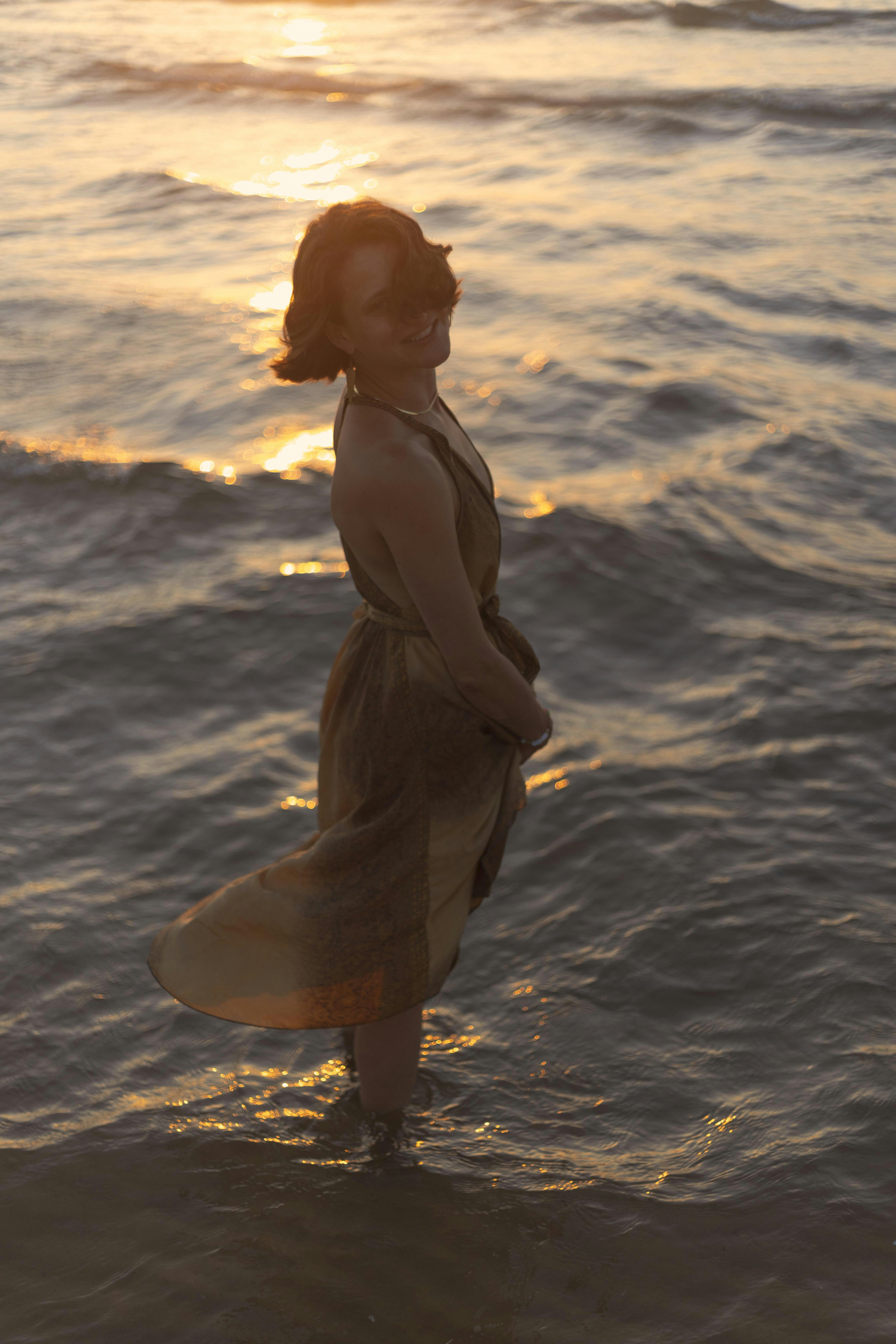 A woman standing in the ocean at sunset photo – Free Photography Image ...