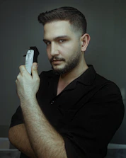 Close-up of a cordless hair trimmer glowing with blue neon light on a dark gray surface.
