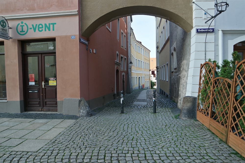 a cobblestone street with an arch leading to a store