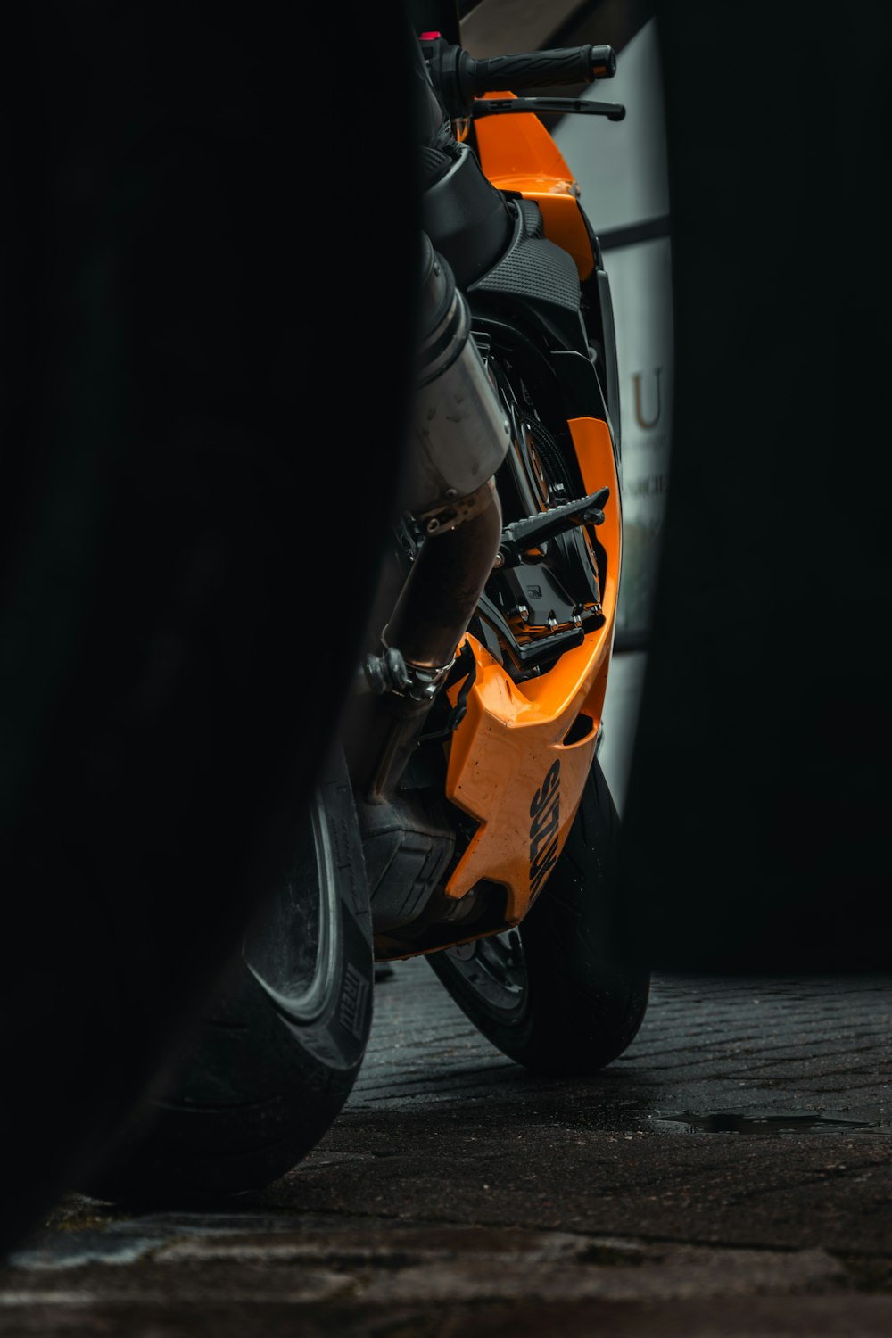 a close up of an orange motorcycle parked in a parking lot