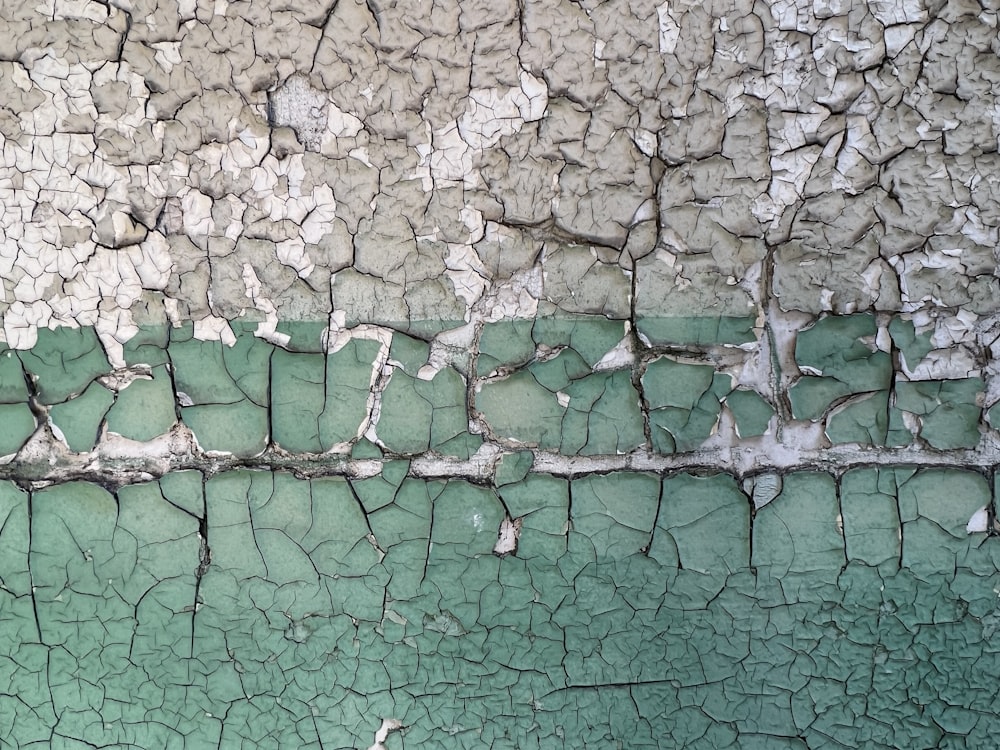 a green and white wall with cracks in it