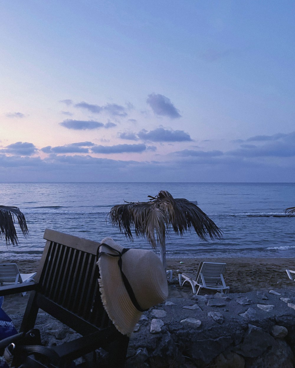 a chair and a hat on a rocky beach