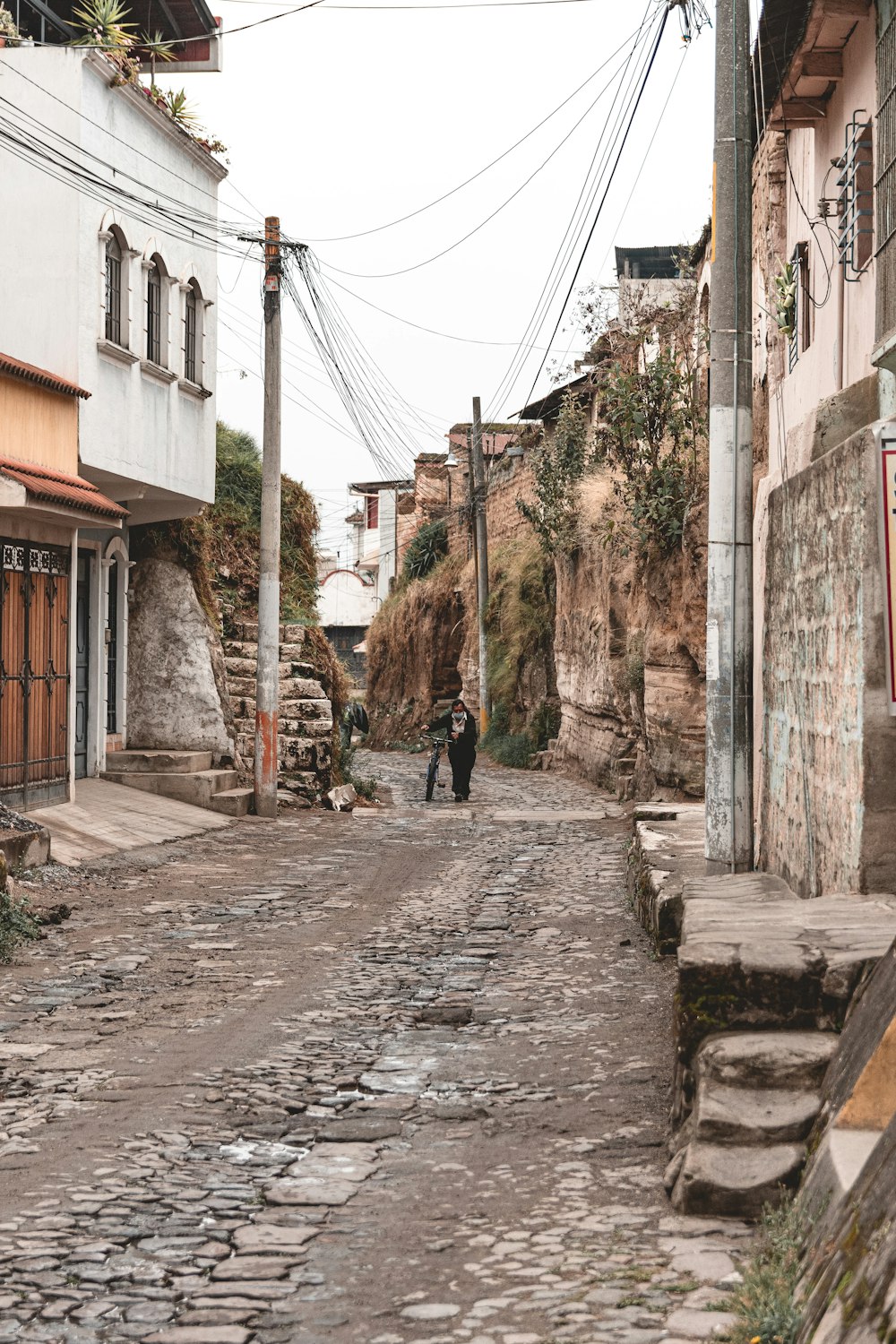 a couple of people walking down a cobblestone street