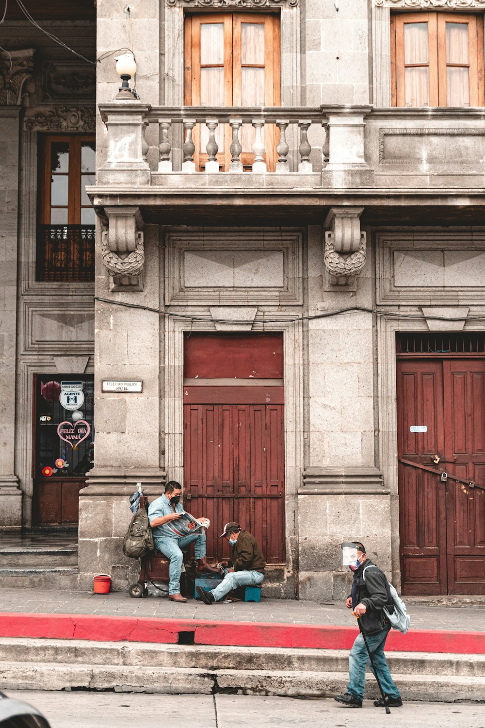a group of people sitting on a bench in front of a building
