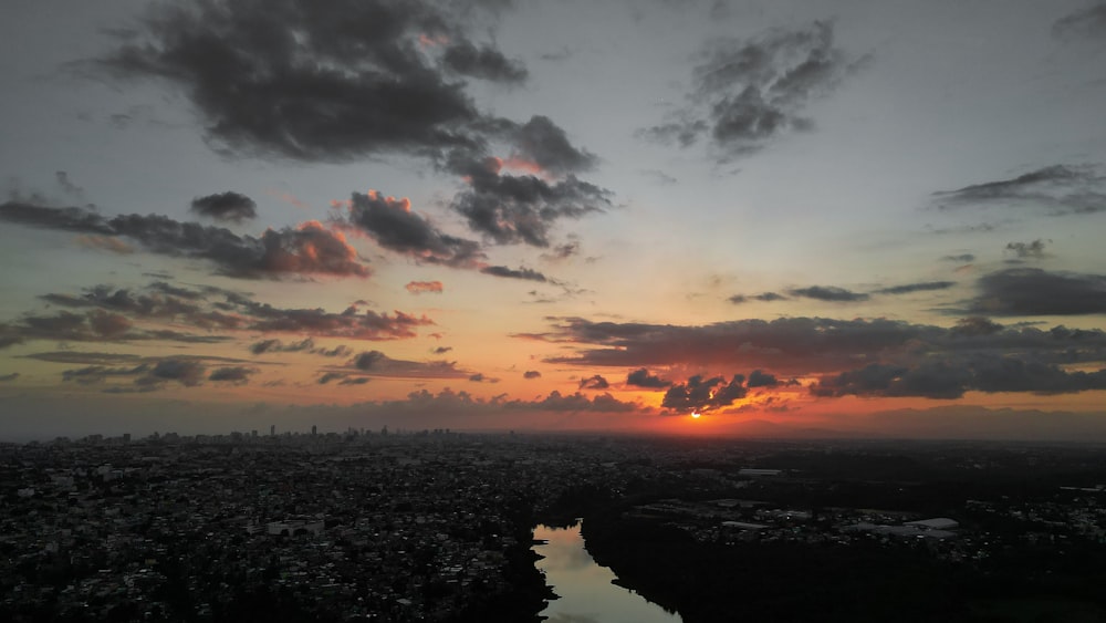 the sun is setting over a city and a body of water