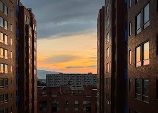 A vibrant NYC street view showing diverse apartment buildings at sunset.