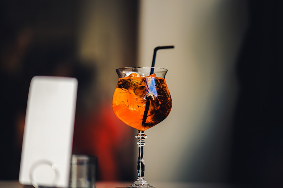 a glass filled with a drink sitting on top of a table,