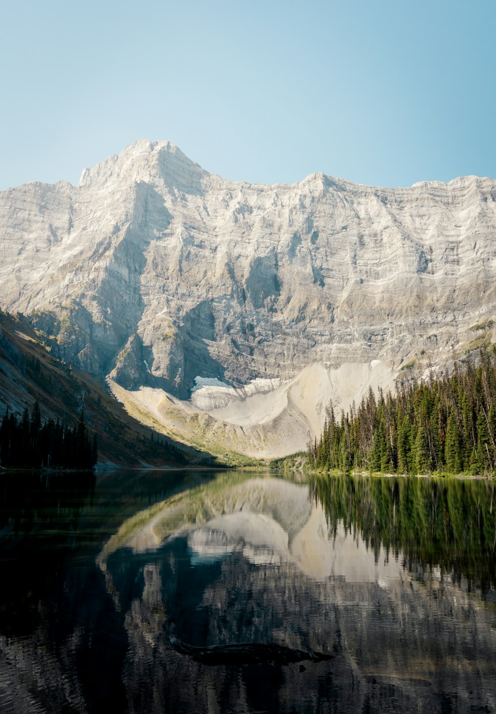 a mountain range is reflected in the still water of a lake