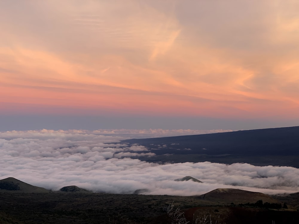 a view of the clouds and mountains from the top of a hill