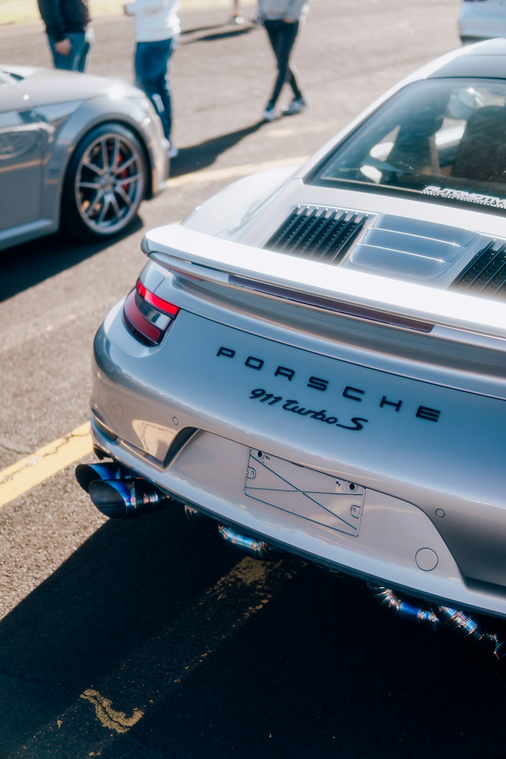 a silver porsche parked on the side of the road