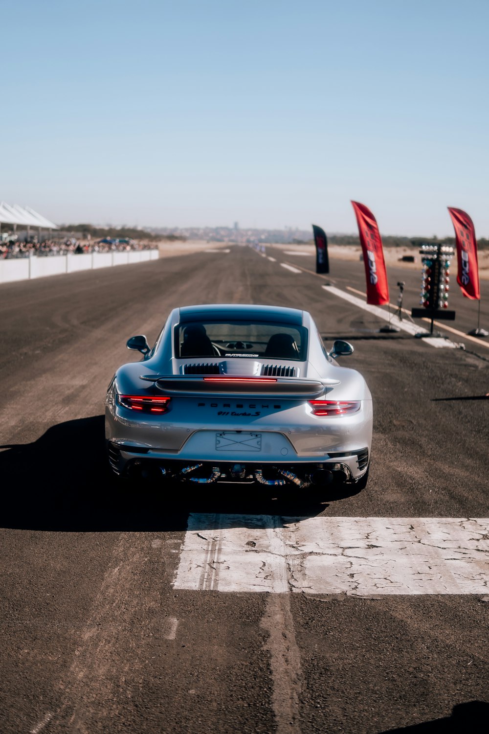 a silver sports car driving down a race track