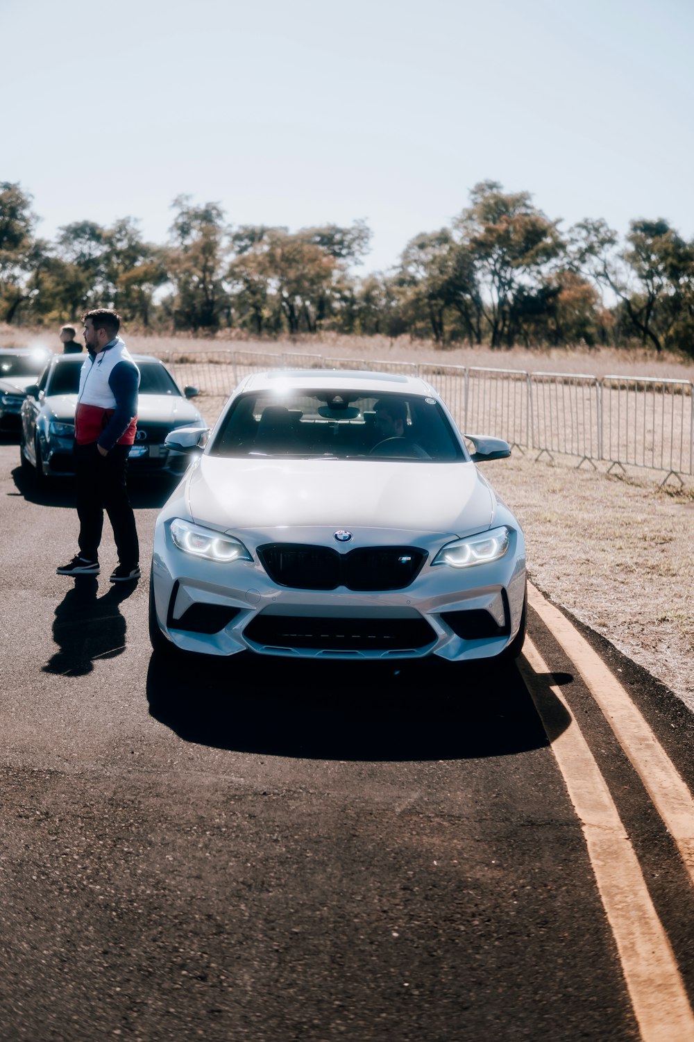 a man standing next to a white car on a road