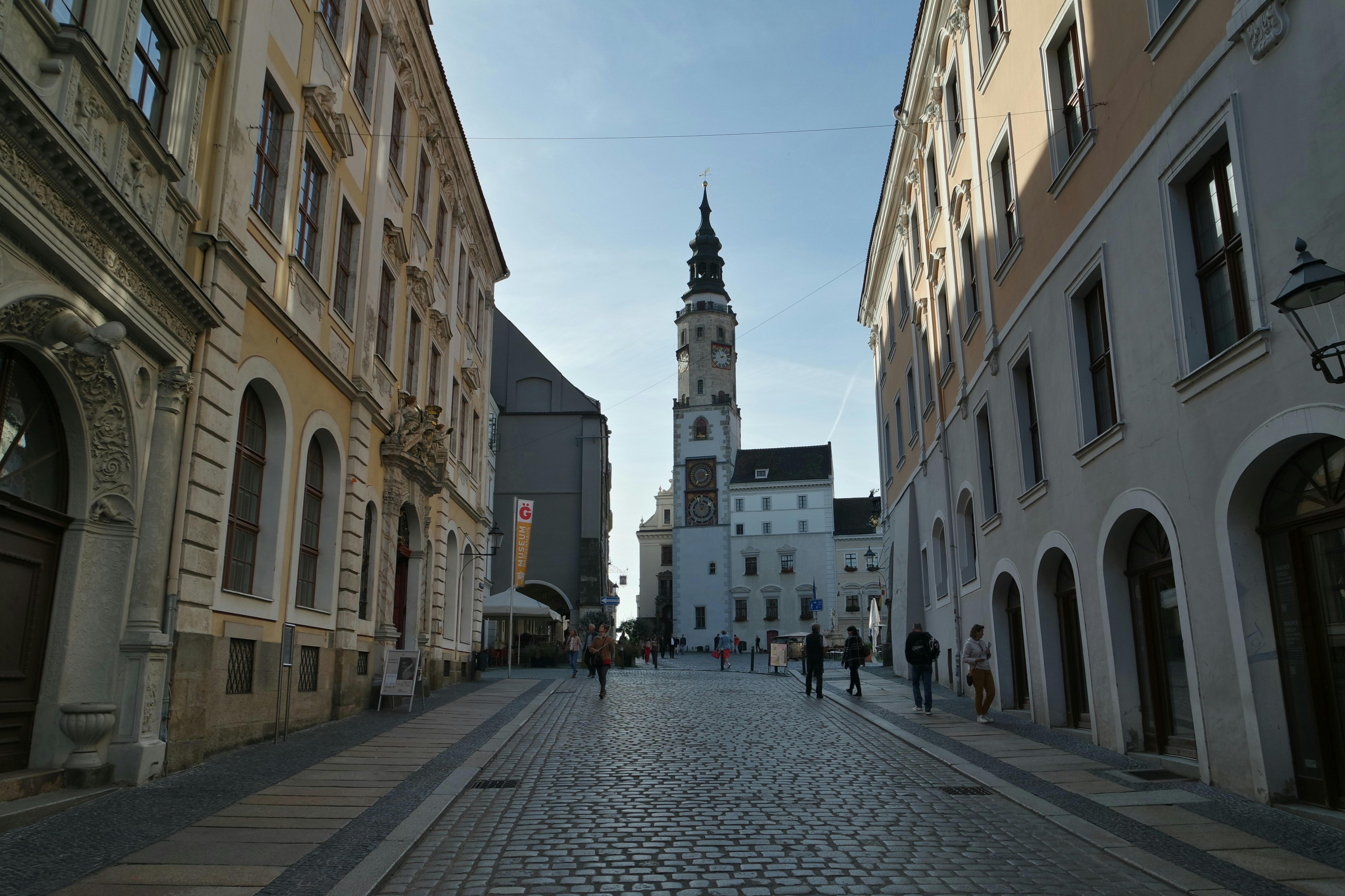 a cobblestone street with a clock tower in the background