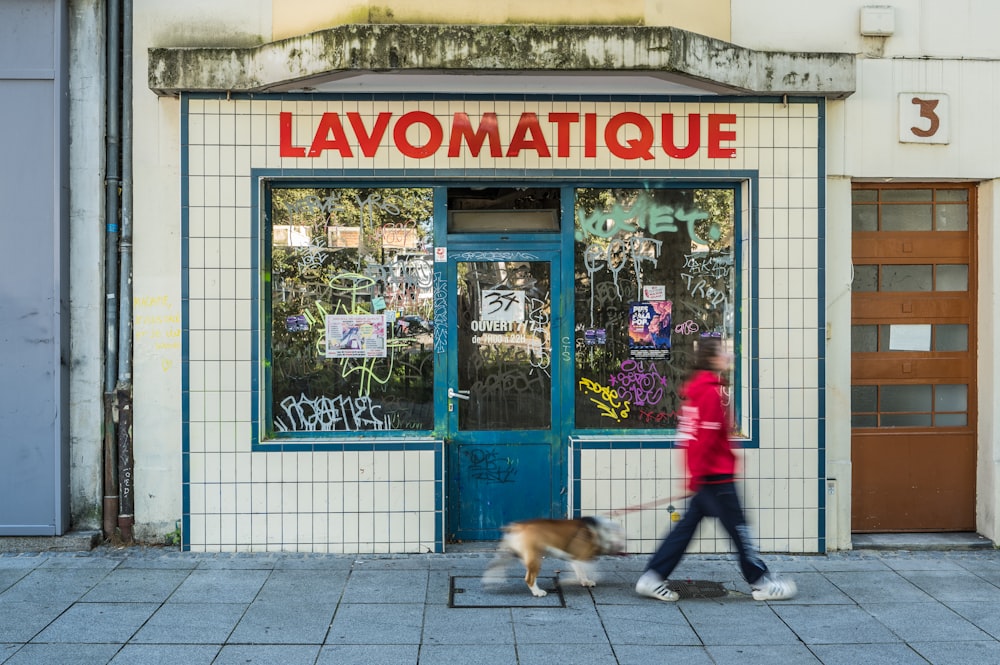 a woman walking a dog in front of a store