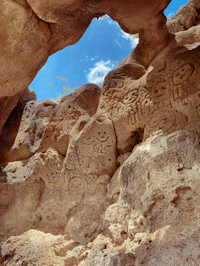 a rock formation with carvings on it and a sky background